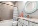Bathroom with a tub, shower, herringbone pattern on the walls, and a round mirror over the vanity at 1330 Mineo Dr, Punta Gorda, FL 33950