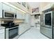 Well-lit kitchen showcasing stainless steel appliances, white cabinets, and tile flooring, creating a clean and functional space at 1374 Grebe Dr, Punta Gorda, FL 33950