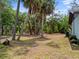 View of the side yard and back of the house showing mature trees at 1510 Orlando Blvd, Port Charlotte, FL 33952