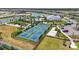 Aerial view of the community's blue and green pickleball courts nestled among lush landscaping and a pond at 16079 Bandermill Dr, Port Charlotte, FL 33953