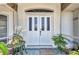 Elegant front door with glass panels and a quaint porch setting, complemented by lush greenery and decorative accents at 17210 Chase Ave, Port Charlotte, FL 33948