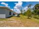 The backyard offers an outdoor seating area surrounded by green grass and trees at 21310 Quesada Ave, Port Charlotte, FL 33952