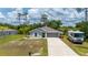 Inviting single-story home with a gray exterior, landscaped front yard and a two-car garage at 21310 Quesada Ave, Port Charlotte, FL 33952