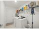 Well-lit laundry room with modern white washer and dryer, and storage shelves at 21310 Quesada Ave, Port Charlotte, FL 33952