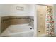 Bathroom featuring a tub with brown tile accents, and a glass shower with a decorative orange shower curtain at 2336 Redfern St, Port Charlotte, FL 33948