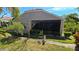 Landscaped backyard featuring green grass, tropical trees, and a screened lanai, offering a private outdoor space at 26073 Feathersound Dr, Punta Gorda, FL 33955