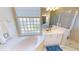 Bright bathroom featuring a tub with glass block window, white vanity, and glass-enclosed shower at 26073 Feathersound Dr, Punta Gorda, FL 33955