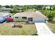 Charming home with well-manicured lawn, flowering plants, mature trees and driveway leading to the garage at 3080 Saint James St, Port Charlotte, FL 33952