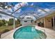 Screened-in pool area featuring a kidney-shaped pool with a tiled border, spacious patio, and lush backyard at 3080 Saint James St, Port Charlotte, FL 33952