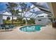 Screened-in pool with clear water, surrounded by a spacious patio, lounge chairs, and lush landscaping at 3080 Saint James St, Port Charlotte, FL 33952