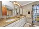 Bathroom featuring double sinks with granite countertops, decorative mirrors, and stylish lighting fixtures at 3663 Sterling Rd, Venice, FL 34293