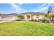 Charming single-story home featuring a lush green lawn, beautiful landscaping, and an attached two-car garage at 474 Lomond Dr, Port Charlotte, FL 33953