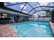 Large screened-in pool with brick pavers, outdoor dining, and lounging area at 543 Mayview Nw Ave, Port Charlotte, FL 33952