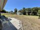 Great backyard with beautiful tropical trees, green grass and a stone patio with seating at 700 Dolphin Pkwy, Punta Gorda, FL 33950