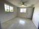 Bedroom with terrazzo flooring, ceiling fan, and natural light from dual windows at 700 Dolphin Pkwy, Punta Gorda, FL 33950