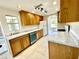 Bright kitchen features tile flooring, wood cabinets, stainless-steel dishwasher, and white appliances at 700 Dolphin Pkwy, Punta Gorda, FL 33950