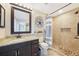 Stylish bathroom featuring granite counters, dark wood cabinetry, walk-in shower with tile surround, and coastal decor at 7333 Watson Ln, Port Charlotte, FL 33981