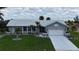 Charming one-story home featuring a well-manicured lawn, mature palm trees and a white tile roof at 745 Monaco Dr, Punta Gorda, FL 33950
