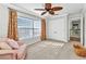 Bright bedroom featuring a ceiling fan, large windows, and neutral carpeting at 9239 Impala Cir, Port Charlotte, FL 33981
