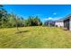 Large backyard with green lawn, trees, and a glimpse of screened patio at 10995 Pinot Dr, Venice, FL 34293