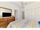 Comfortable bedroom featuring a wooden dresser with a mirror, closet and a bed with patterned bedding at 10995 Pinot Dr, Venice, FL 34293