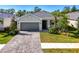 Charming single-story home with a well-manicured lawn, paver driveway, and gray tiled roof at 10995 Pinot Dr, Venice, FL 34293