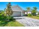 Charming home with well-kept lawn, beautiful plants, palm trees, and gray paver driveway at 10995 Pinot Dr, Venice, FL 34293