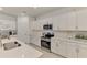 Bright kitchen features white cabinetry, quartz countertops, stainless appliances, tile flooring, and modern fixtures at 10995 Pinot Dr, Venice, FL 34293