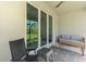 View of the house patio with outdoor seating and sliding glass doors to the home's interior at 10995 Pinot Dr, Venice, FL 34293