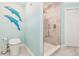 Well-lit bathroom featuring a toilet and shower with marbled tile, plus charming dolphin wall decor at 12596 Bacchus Rd, Port Charlotte, FL 33981