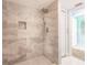 Walk-in shower featuring gray marbled-tile, niches for toiletries, and rainfall shower head at 12596 Bacchus Rd, Port Charlotte, FL 33981