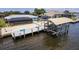 An aerial view of the dock with boat lift with a covered pool in the background at 12596 Bacchus Rd, Port Charlotte, FL 33981