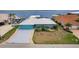 Charming waterfront home featuring a large driveway, turquoise exterior paint and a metal roof and scenic views at 12596 Bacchus Rd, Port Charlotte, FL 33981