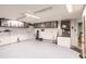 Spacious garage featuring overhead storage cabinets, speckled epoxy flooring, and ample lighting at 12596 Bacchus Rd, Port Charlotte, FL 33981
