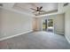 Bedroom features a ceiling fan, tray ceiling, and sliding glass doors at 13972 Chesswood Ln, Port Charlotte, FL 33981