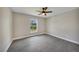 An empty bedroom with new flooring, a fan, and a window overlooking the lawn at 13972 Chesswood Ln, Port Charlotte, FL 33981