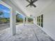 A covered patio with a ceiling fan, gray pavers, and a view of the wooded area at 13972 Chesswood Ln, Port Charlotte, FL 33981