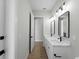 Bright bathroom with double sinks, modern lighting, black hardware and wood look floors at 15504 Melport Cir, Port Charlotte, FL 33981