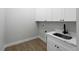 A neutral laundry room with wooden floors and bright white storage cabinets and sink at 15504 Melport Cir, Port Charlotte, FL 33981