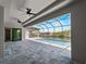 Enclosed pool area with a canal view, features modern pavers, ceiling fans, and a screened enclosure at 15504 Melport Cir, Port Charlotte, FL 33981
