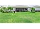 Beautifully landscaped backyard with lush green lawn, palm trees, and a covered patio area at 17556 Winding Wood Ln, Punta Gorda, FL 33982