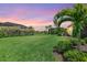 Backyard at dusk featuring tropical landscaping and a well maintained lawn at 17556 Winding Wood Ln, Punta Gorda, FL 33982