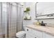 Well-lit bathroom featuring a vanity with granite countertop, modern fixtures, decorative shelves, and a shower with curtain at 17556 Winding Wood Ln, Punta Gorda, FL 33982