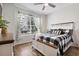 Bright bedroom featuring a ceiling fan, a large window, and a cozy bed with stylish black and white bedding at 17556 Winding Wood Ln, Punta Gorda, FL 33982