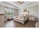 Well-lit bedroom featuring tray ceiling, stylish bed with farmhouse accents, and hardwood floors at 17556 Winding Wood Ln, Punta Gorda, FL 33982