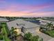 Charming home featuring a three-car garage, paver driveway, and beautiful landscaping under a colorful sky at 17556 Winding Wood Ln, Punta Gorda, FL 33982