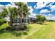 Green backyard with palm trees and view of screened in pool, back of house, with green grass at 17924 Corkwood Bend Trl, Punta Gorda, FL 33982