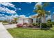 Exterior elevation view of home with three-car garage, landscaped garden with pink flowers and palm tree at 17924 Corkwood Bend Trl, Punta Gorda, FL 33982