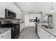 Bright kitchen with stainless steel appliances, granite counters, white cabinetry and a view of the dining area at 17924 Corkwood Bend Trl, Punta Gorda, FL 33982