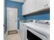 Functional laundry room with upper cabinets and modern appliances and blue walls at 17924 Corkwood Bend Trl, Punta Gorda, FL 33982
